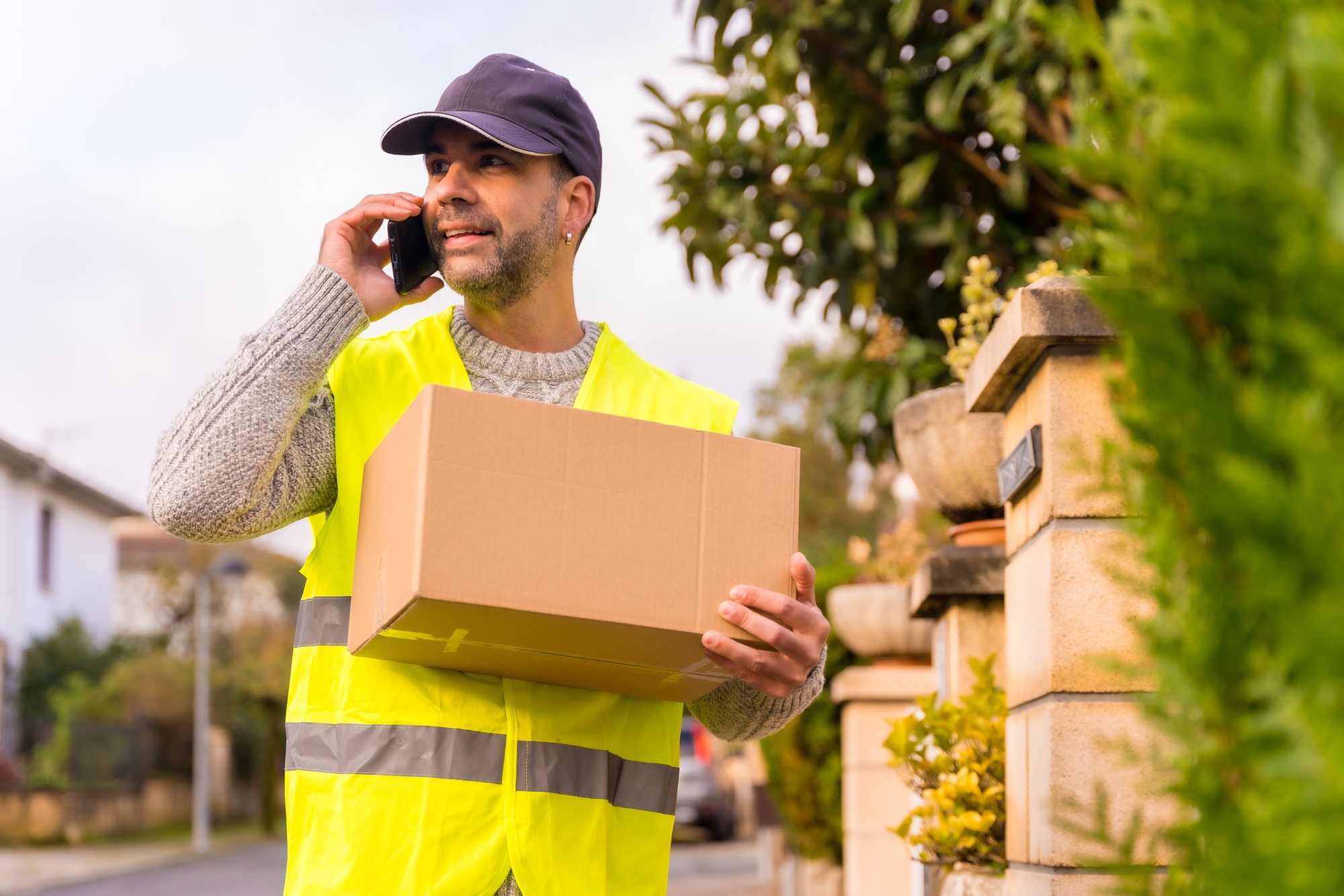 Package delivery carrier with a box from an online store, calling the customer