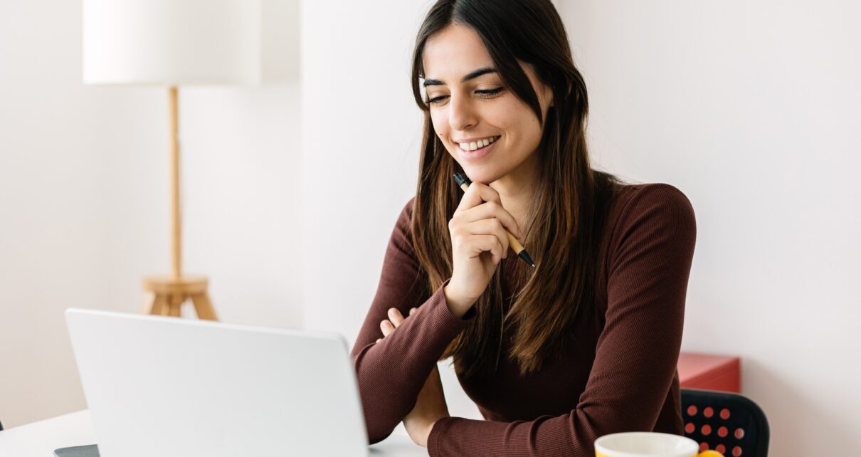 Portrait of young adult student sitting on table using laptop learning online