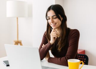 Portrait of young adult student sitting on table using laptop learning online