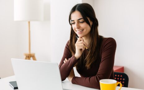 Portrait of young adult student sitting on table using laptop learning online