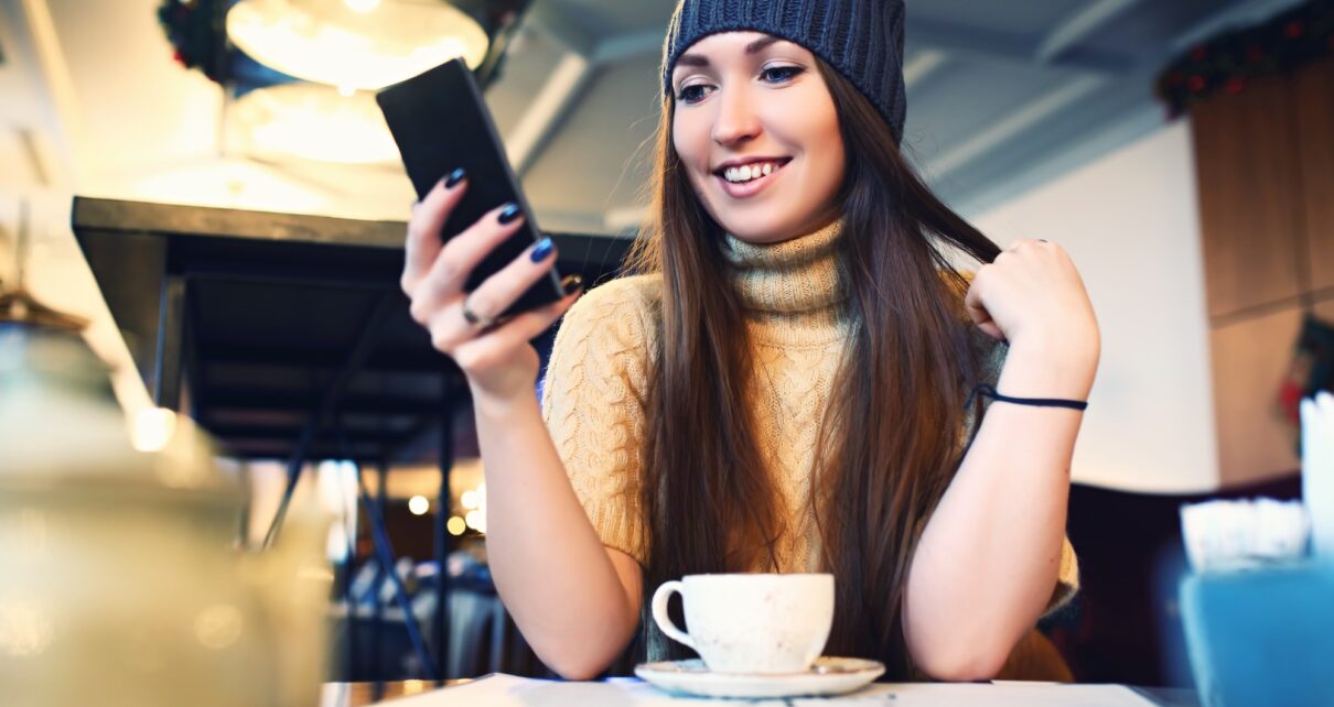 Portret of young female reading sms on the phone in cafe. Toned. Selective focus.