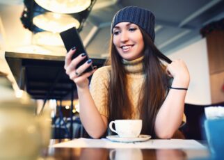 Portret of young female reading sms on the phone in cafe. Toned. Selective focus.