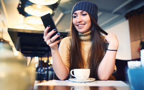 Portret of young female reading sms on the phone in cafe. Toned. Selective focus.
