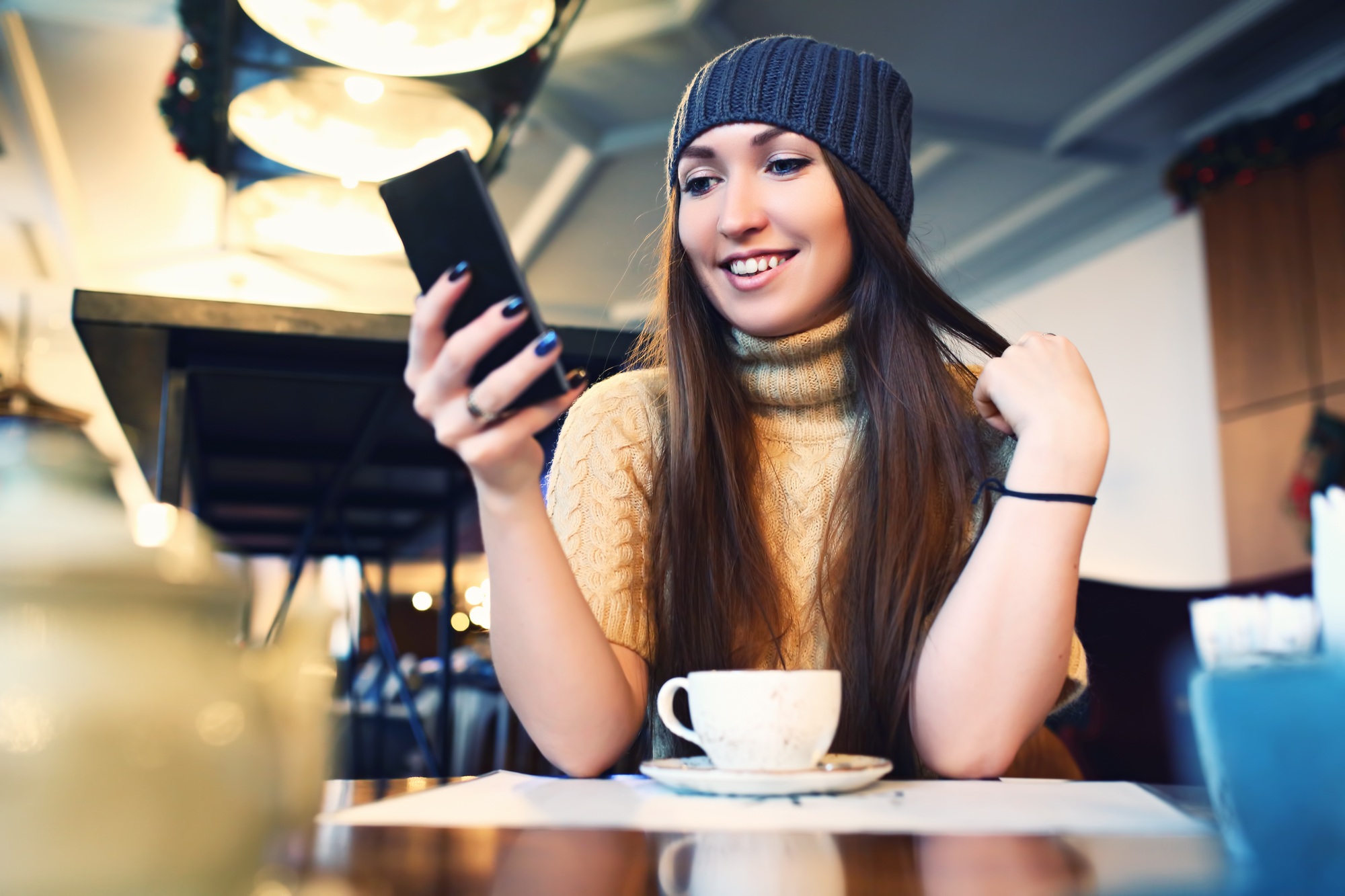 Portret of young female reading sms on the phone in cafe. Toned. Selective focus.