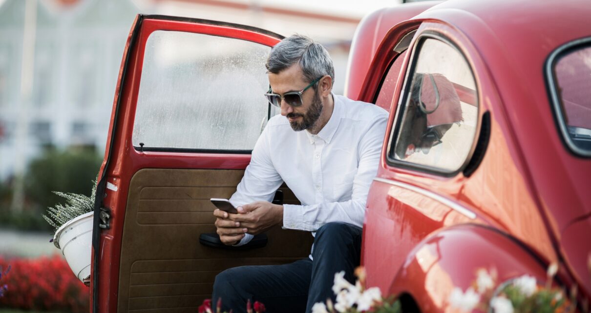 The man writes sms in the red oldtimer
