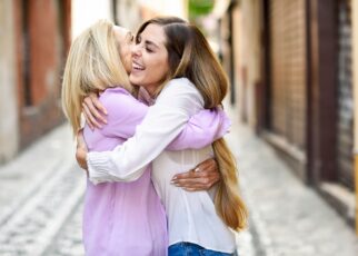 Happy mature woman hugging her daughter in the city