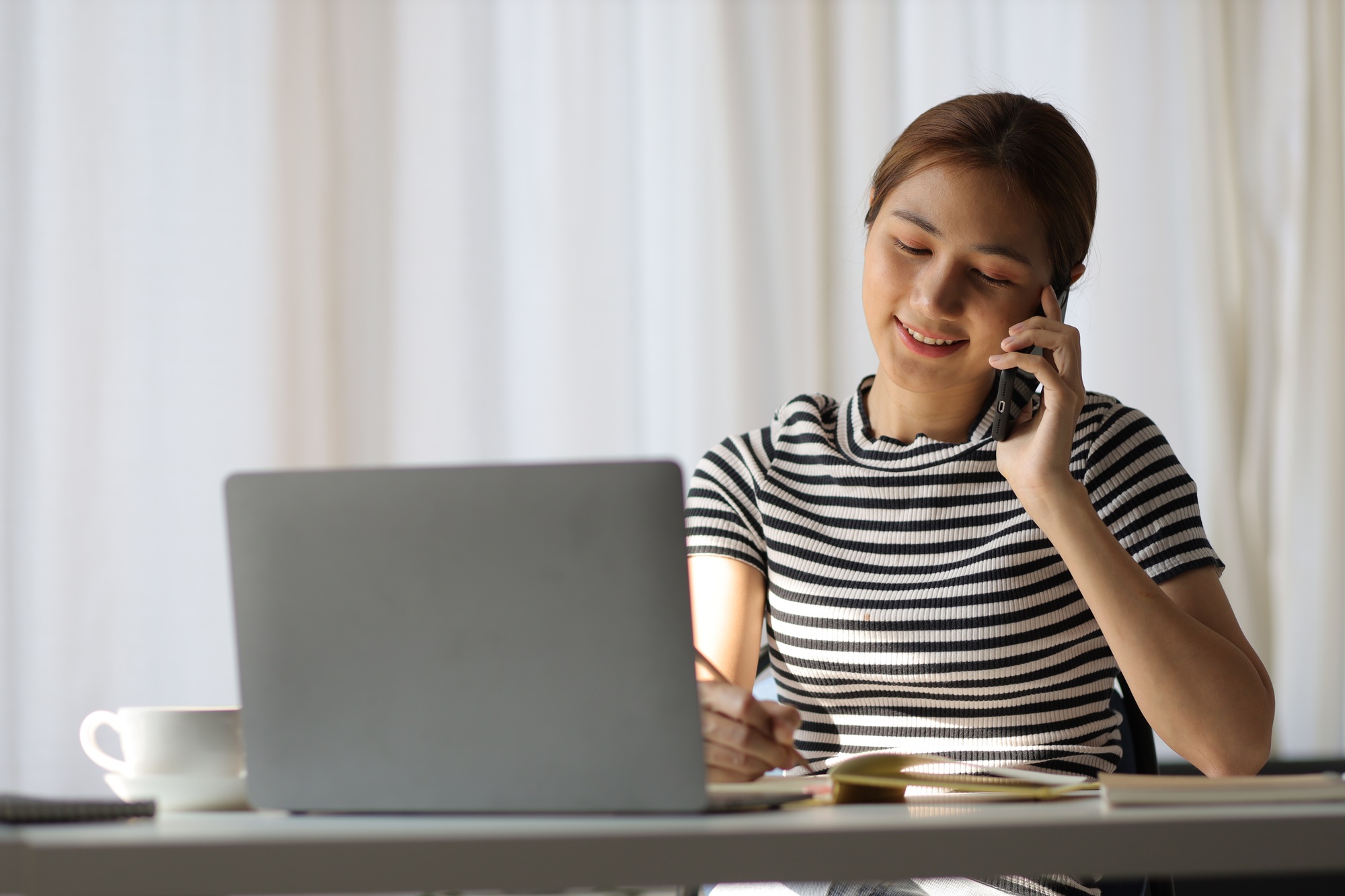 Woman on call with someone and reading work notebook.