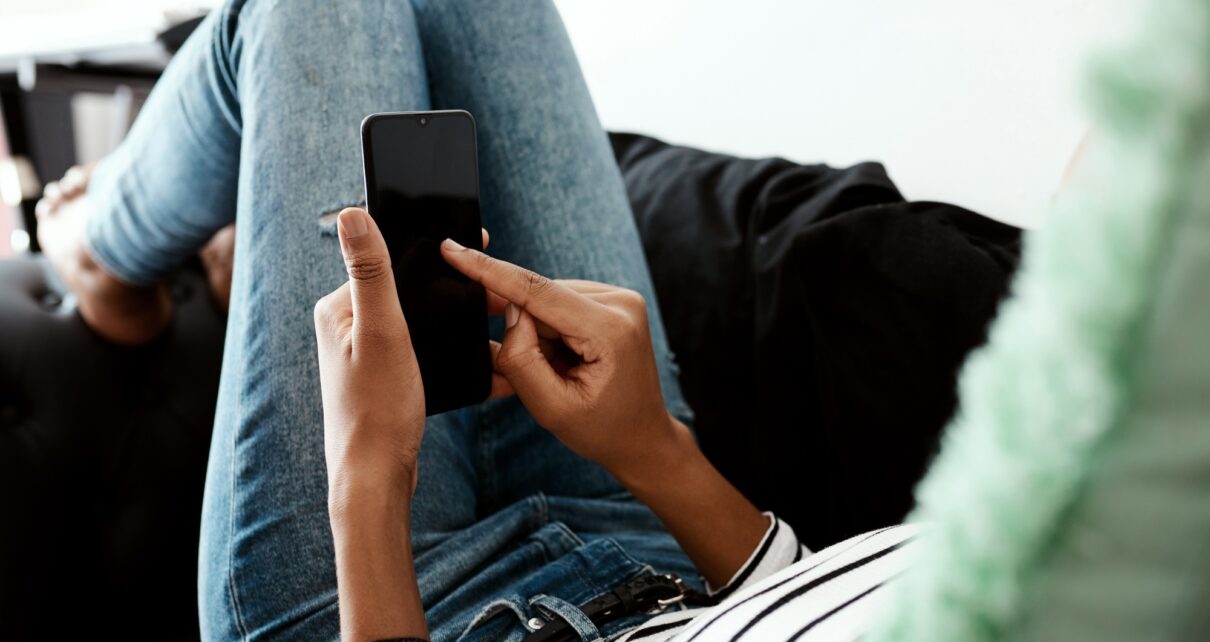 And send...Cropped shot of a woman using a smartphone on the sofa at home.