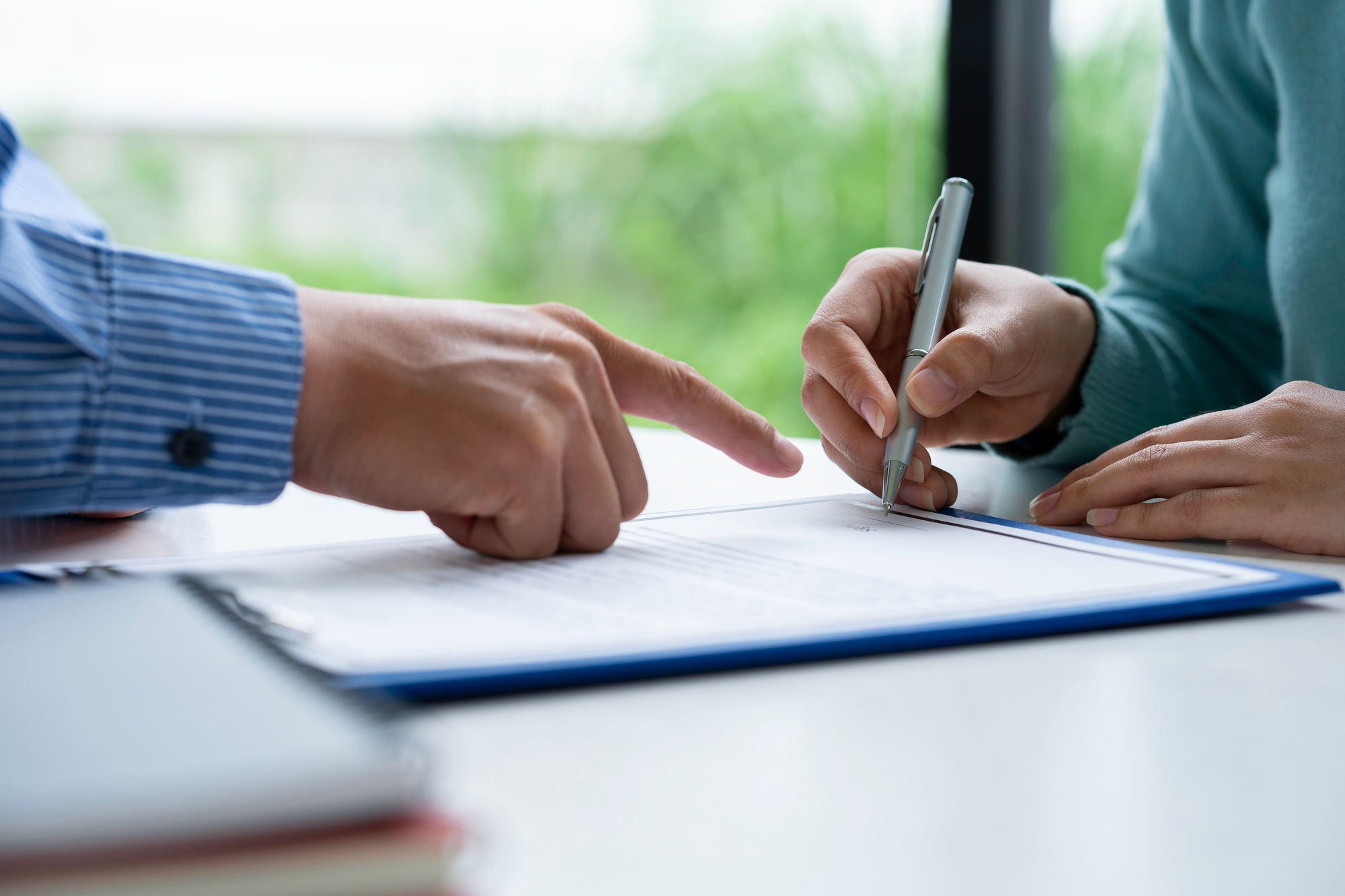 Businesswoman signing a document or application form in a folder, Businessmen hand's pointing where
