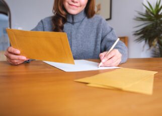 Closeup image of a woman writing on a letter and envelopes