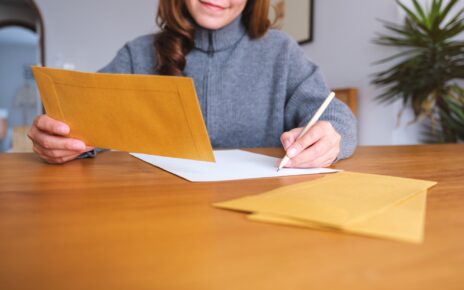 Closeup image of a woman writing on a letter and envelopes
