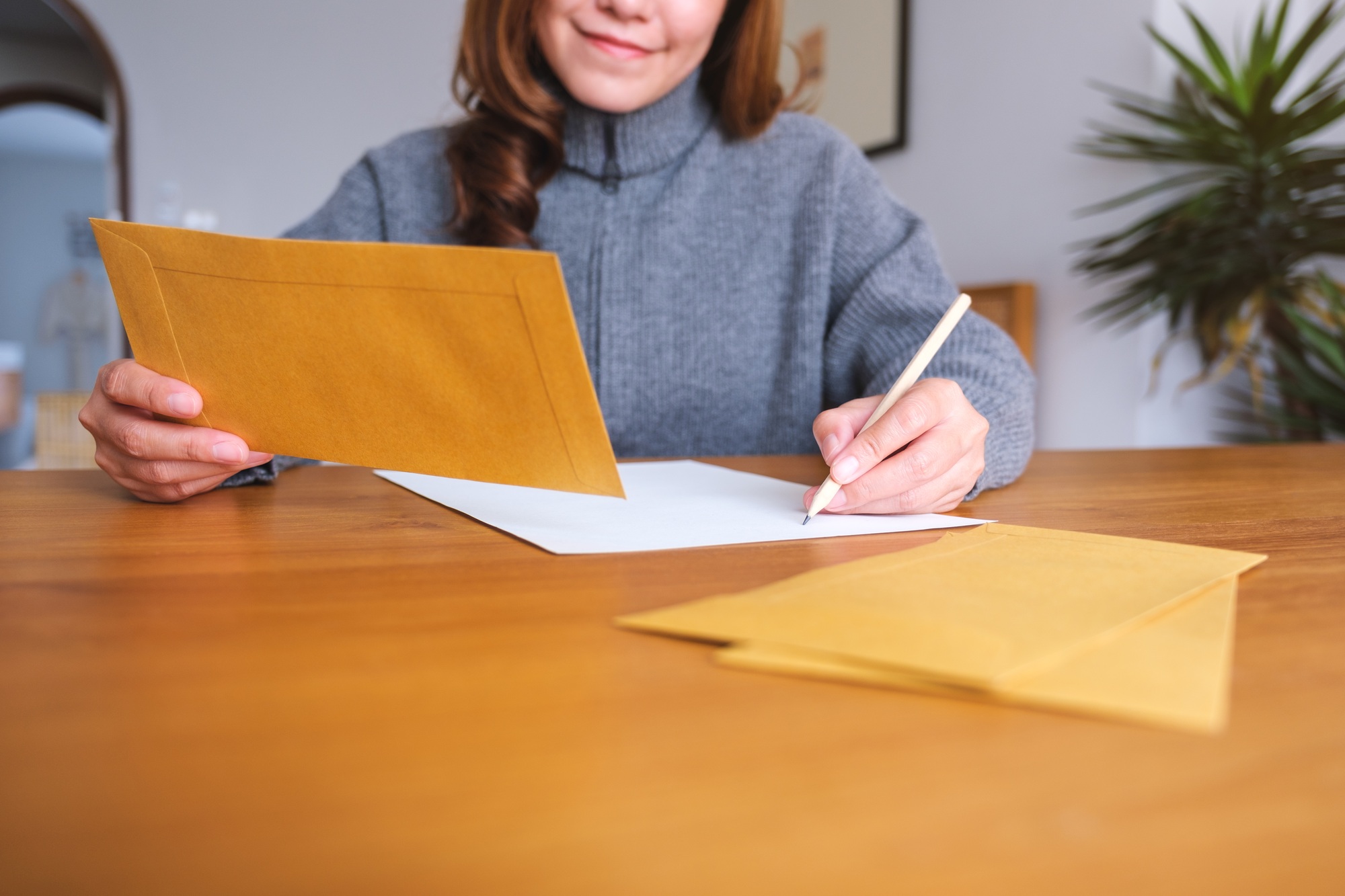Closeup image of a woman writing on a letter and envelopes