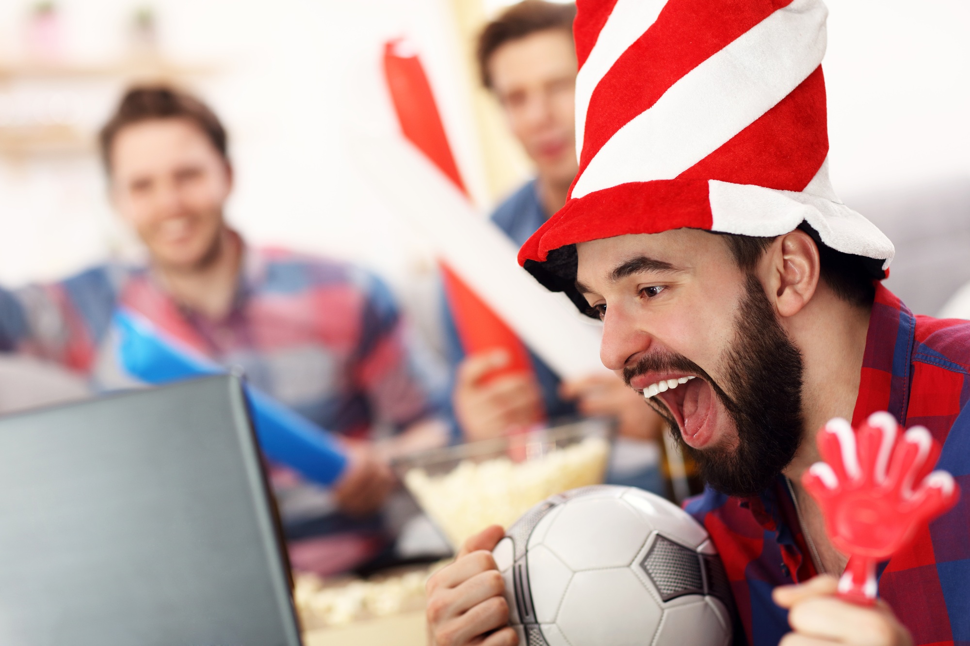 Happy male friends cheering and watching sports on tv